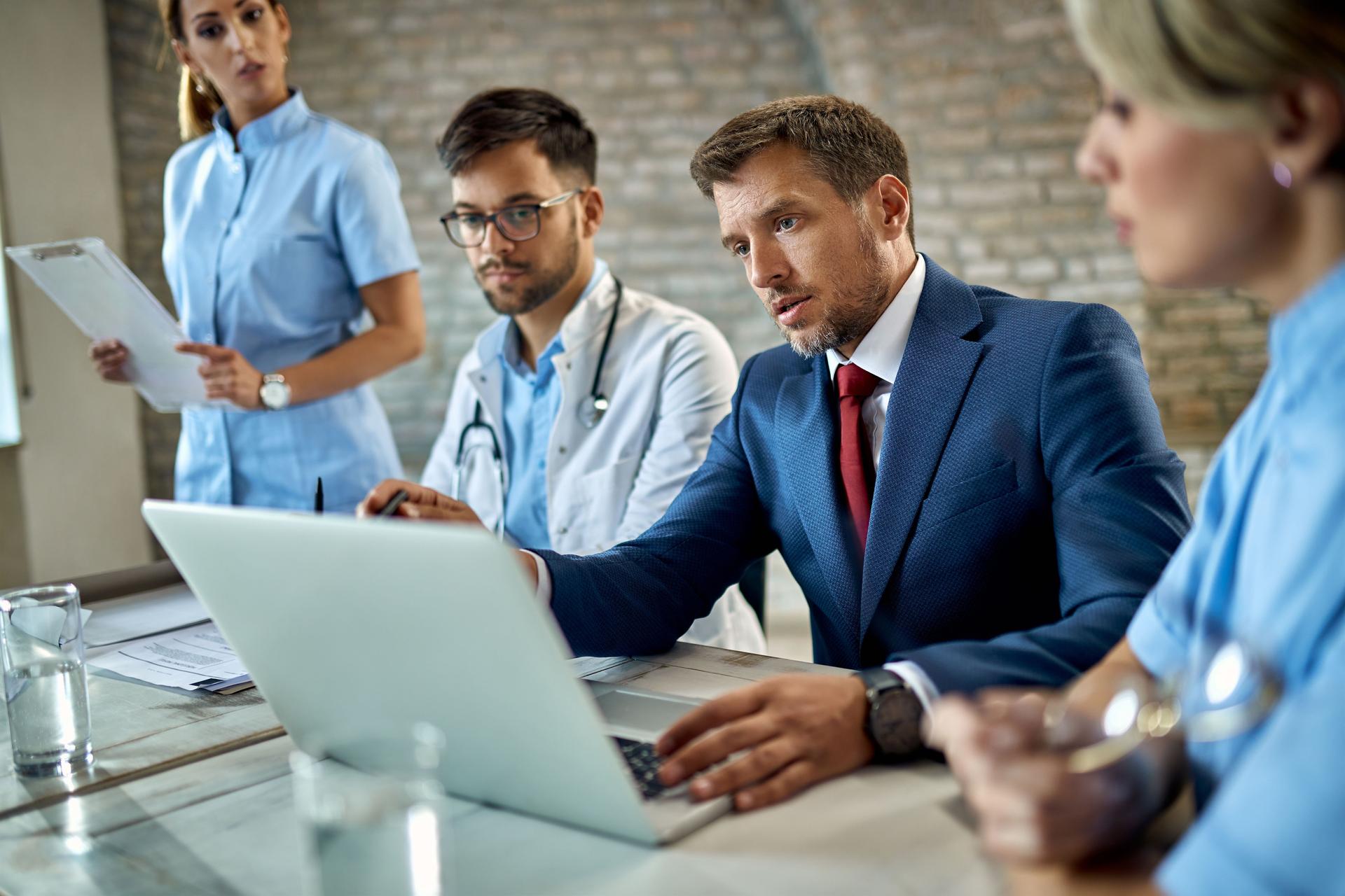 Businessman and group of doctors using laptop during the meeting.